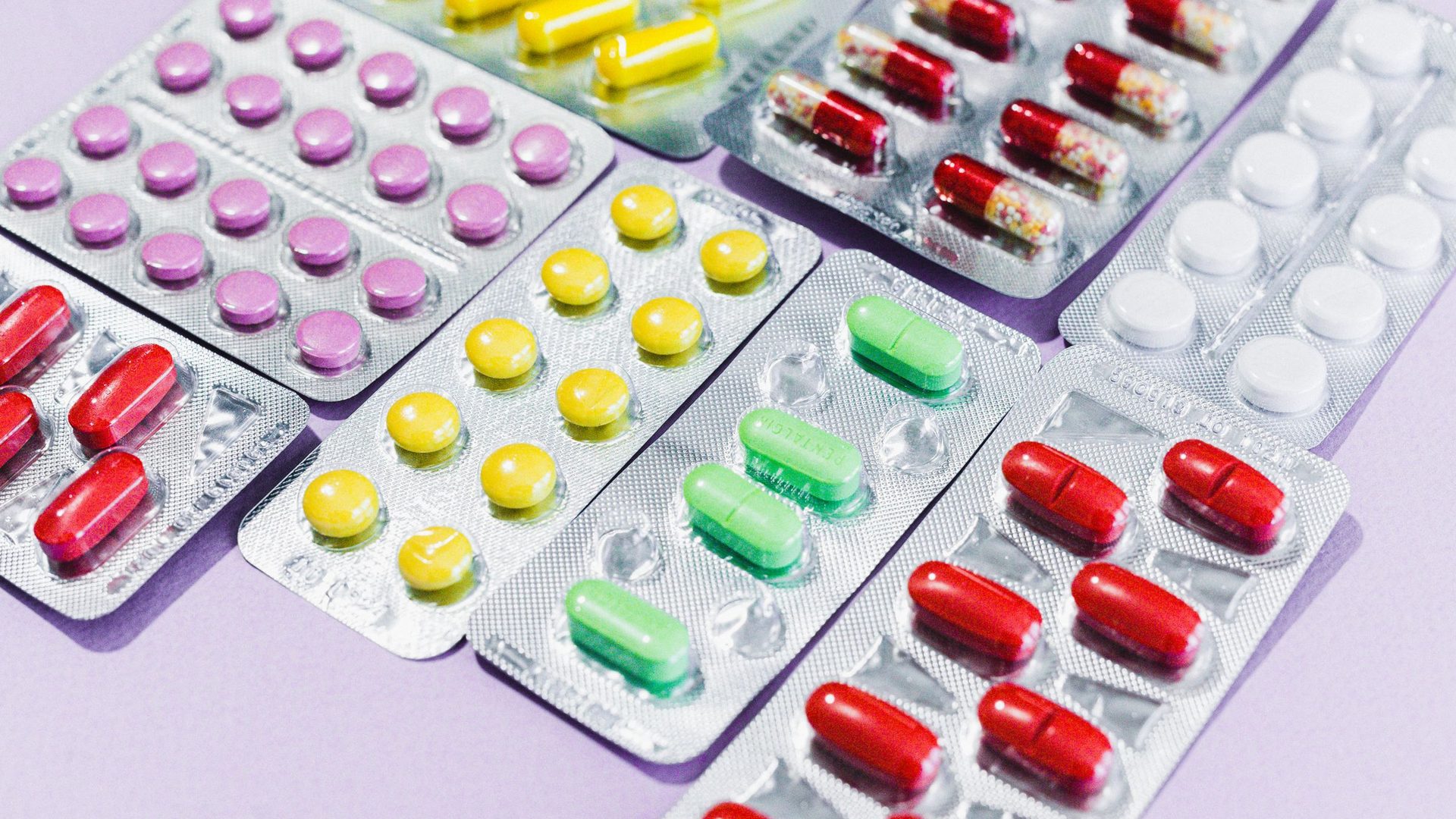 Plaquettes de médicaments de toutes les couleurs, posées les unes sur les autres.